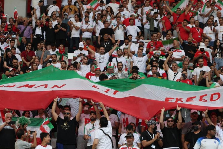 Supporters iraniens célébrant leur équipe sous le drapeau national, alors que l’accès aux matches du Mondial 2026 organisés aux États-Unis s’annonce compromis.