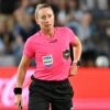 Une arbitre de football en action sur la pelouse.