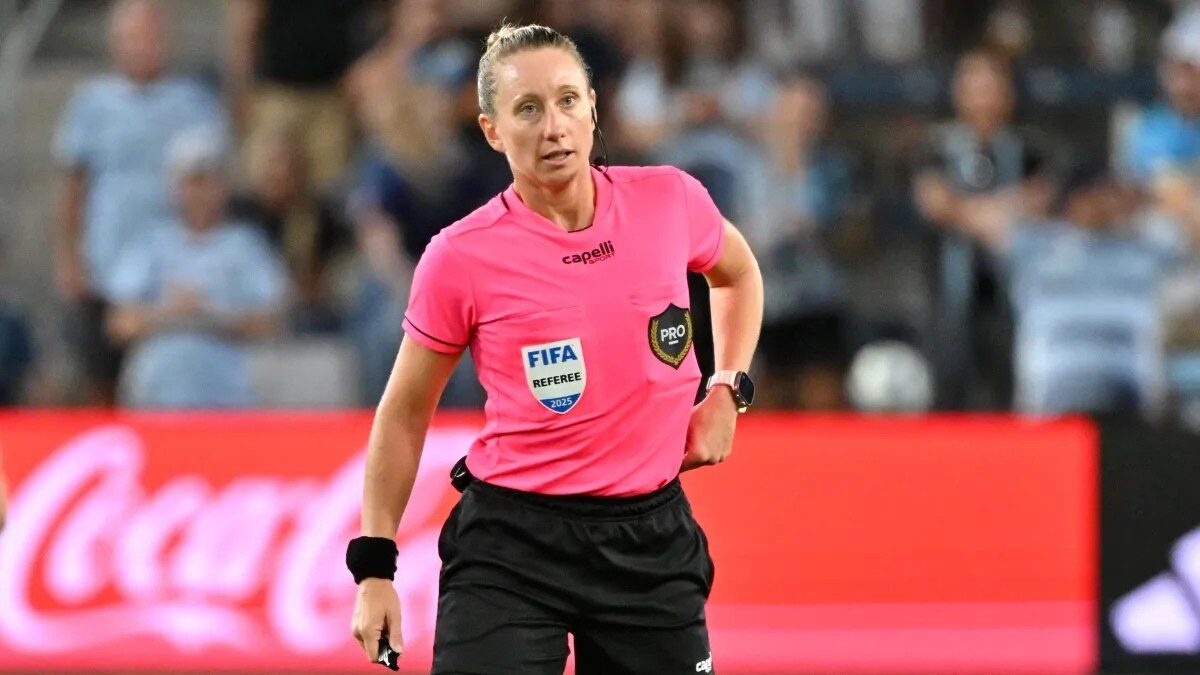 Une arbitre de football en action sur la pelouse.